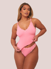 Woman wearing a pink lingerie set against a plain background